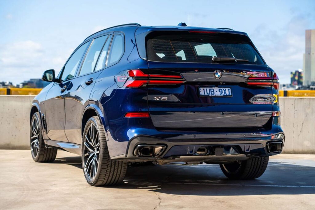 Rear view of the updated 2025 BMW X5 xDrive40i in blue color with sporty alloy wheels and sleek LED tail lights