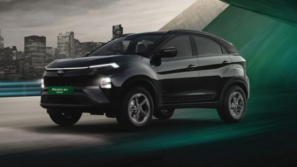 A dynamic shot of the all-black Tata Nexon EV ADAS #DARK Edition driving on a road with a futuristic city background, showcasing its sleek design and "Nexon.ev #DARK" badging.