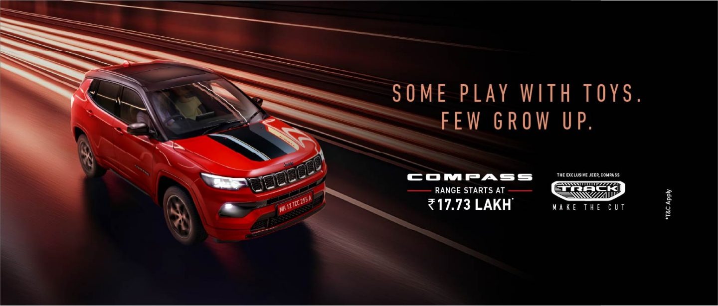 Jeep Compass Track Edition का एक विज्ञापन बैनर, लाल रंग की एसयूवी और "SOME PLAY WITH TOYS. FEW GROW UP." टैगलाइन दिखा रहा है, जिसमें Jeep Compass Track Edition Price ₹17.73 लाख से शुरू होने का उल्लेख है।