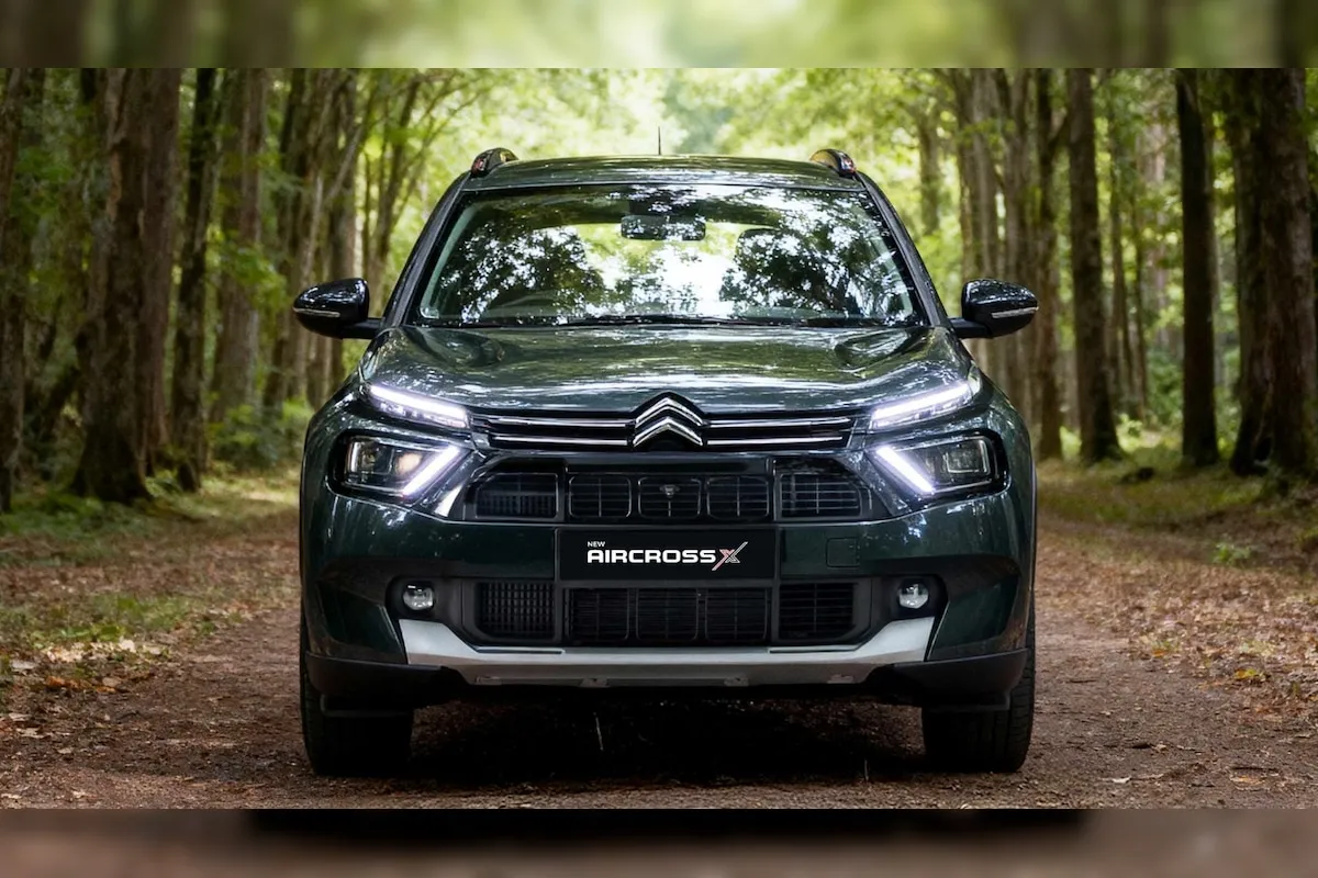 Deep Forest Green रंग की Citroen Aircross X SUV का फ्रंट व्यू, जो जंगल जैसे बैकग्राउंड में खड़ी है। यह कार New Citroen Aircross X Launch का हिस्सा है।