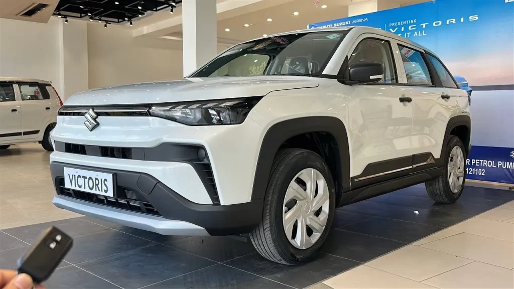 शोरूम के अंदर खड़ी सफेद Maruti Suzuki Victoris SUV, जिसकी बुकिंग Maruti Suzuki Festive Season Sales में 25,000 से अधिक हुई हैं।