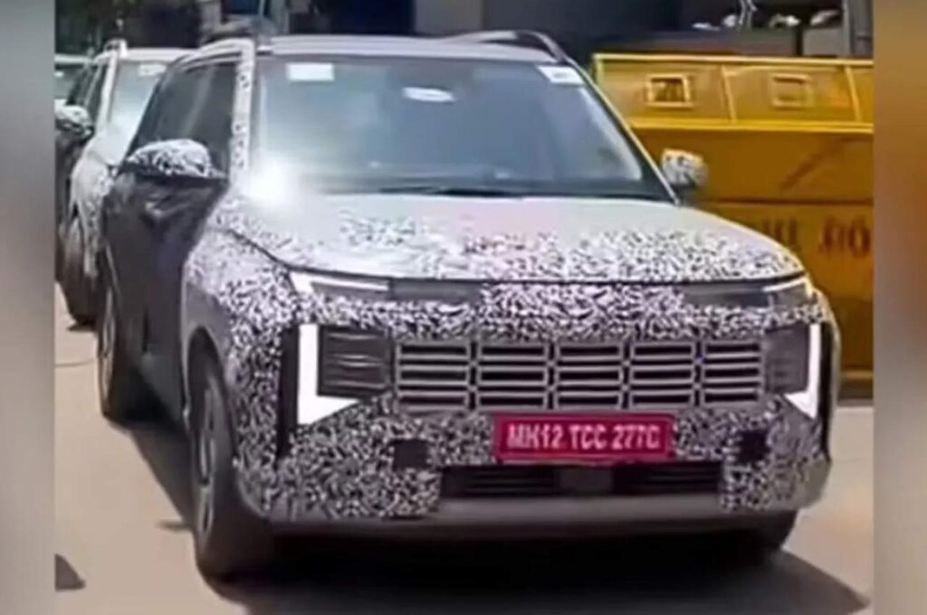 New-Gen Hyundai Venue (छलावरण/परीक्षण इकाई में) का स्पाईशॉट। यह तस्वीर कनेक्टेड टॉप LED स्ट्रिप DRL, क्षैतिज स्लैट्स के साथ पूरी तरह से बदले हुए आयताकार ग्रिल डिज़ाइन और उसके नीचे वर्टिकल रूप से व्यवस्थित लाइटिंग सेटअप वाले ताज़ा फ्रंट फेसिया को दिखाती है।